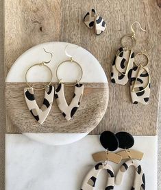 the black and white earrings are next to each other on a marble plate with gold ear wires