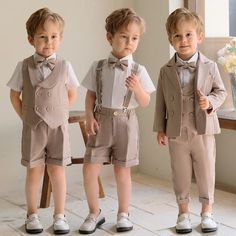 three little boys dressed up in suits and bow ties, standing next to each other