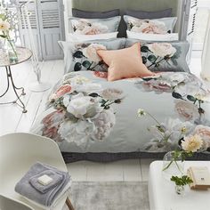 a bed with flowers on it in a bedroom next to a table and chair,