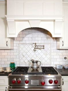 a stove top oven sitting inside of a kitchen next to white cabinets and counter tops