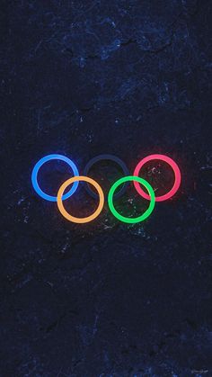 the olympic rings are lit up in different colors and sizes on a black surface with dark background