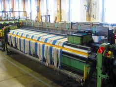 an assembly line in a factory with several machines and machinery on the floor, one being used for weaving fabric