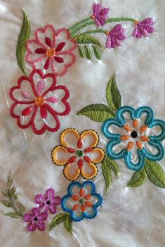 four different colored flowers on a white sheet