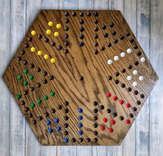 a wooden board game set up on top of a white wood floor with colored dots