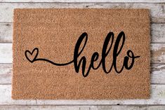 a door mat with the word hello written on it and a heart in black ink