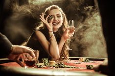 a woman sitting at a table with two wine glasses in front of her and playing cards