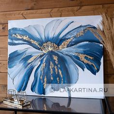 a large blue flower painted on a white canvas next to some dried grass and a candle