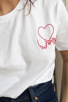 a woman wearing a white t - shirt with a red heart drawn on the chest