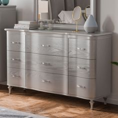 a silver dresser with a mirror on top of it next to a rug and lamp