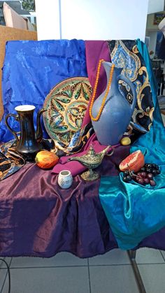 a table topped with lots of assorted items on top of a blue cloth covered table