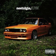 an orange car is parked in the grass near some trees and bushes with words that read nostalgicia ultra