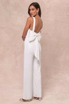 a woman in white jumpsuits with a large bow on the back