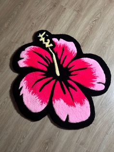 a pink and black flower rug sitting on top of a wooden floor