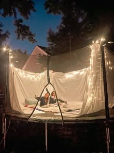 two people are sitting in a tent with fairy lights