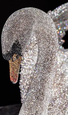 a white swan statue covered in lots of silver sparkles and glitter dusted around it's neck