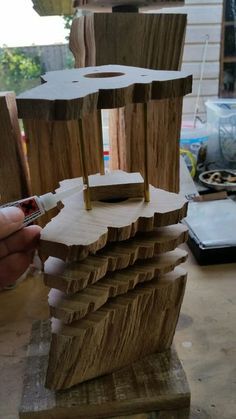 a person holding a piece of wood in front of a wooden structure that has been made out of plywood