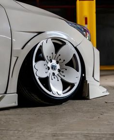 the front wheel of a white car with flowers painted on it's rims