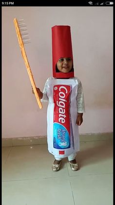 a child in a costume holding a toothbrush and toothpaste on it's head