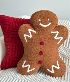 two decorative gingerbreads sitting next to each other on a white bed with red pillows