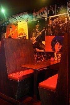 the inside of a restaurant with posters on the wall and wooden booths in front of them