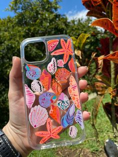 a person holding up a phone case with colorful butterflies on it in front of some trees