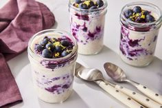 blueberry cheesecake in a jar with spoons next to it on a table