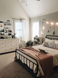 a bedroom with white walls and lights on the ceiling, bedding is made up