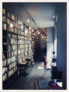 a room filled with lots of books on shelves next to a dining table and chairs