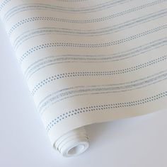 a white and blue striped wallpaper with small dots on the top half of it