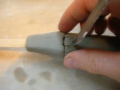 a person using a pair of scissors on a piece of wood with holes in it