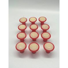 twelve red and white plastic knobs on a white surface