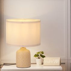 a white lamp sitting on top of a table next to a small potted plant