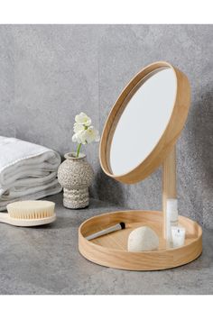 a wooden stand with a mirror, comb and soap on it next to a white flower