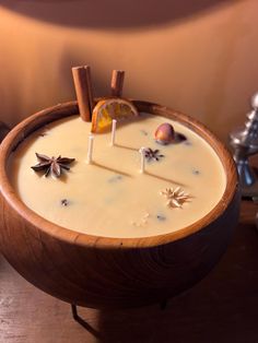 a wooden bowl filled with white liquid and cinnamon stick decorations on top of it's sides