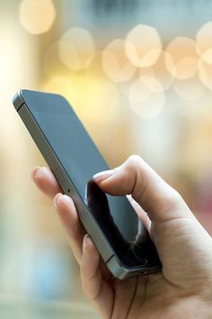 a person holding a cell phone in their hand with blurry lights on the background