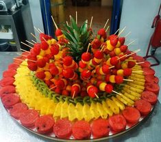 a platter filled with fruits and skewered pineapples on top of each other