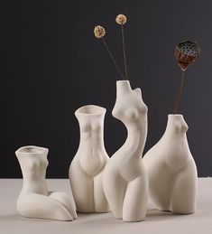 three white vases with flowers in them sitting on a table next to each other