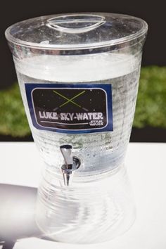 a water dispenser sitting on top of a table next to a green field