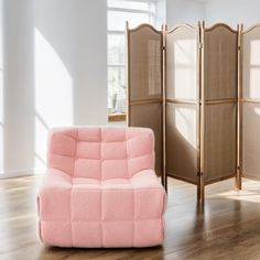 a room divider in the shape of a couch next to a pink chair and wooden floor