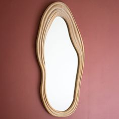 an oval shaped mirror mounted to the side of a wall next to a pink wall