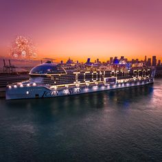 a large cruise ship in the water with fireworks on it's side and buildings in the background