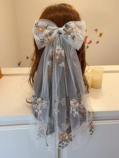 a veil with flowers on it sitting on top of a counter next to a candle