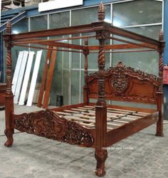 an antique wooden bed frame in front of a building with glass doors and windows behind it