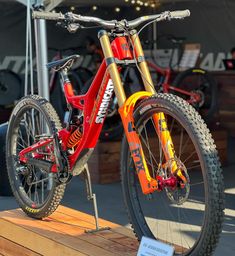 a red and yellow bike sitting on top of a wooden platform