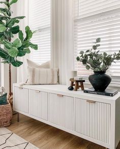 a living room with white furniture and plants on the window sill in front of it