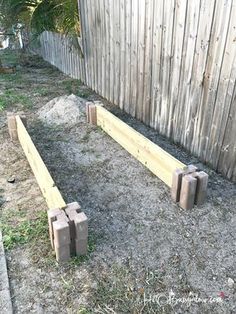 two benches made out of cinder blocks sitting in the grass next to a wooden fence