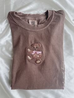 "Embroidered Teddy Bear T-Shirt! -Embroidered on 100% cotton Comfort Colors T-shirt, this design is simple and minimalistic, perfect for every outfit! -Embroidery design measures 2.25\" x 3.5\". -See product pictures for shirt sizing chart. **T-SHIRTS ARE IN UNISEX SIZING AND RUN TRUE TO SIZE. -All t-shirts are handmade on an embroidery machine so there may be slight differences, but we only sell the sweatshirts that meet our high-quality standards. -To maintain the quality of your T-shirt and t Teddy Bear T Shirt, Embroidery Tshirts, Aesthetic Cozy, Brown Teddy Bear, Embroidered Tee, Sweat Shirts, Bear T Shirt, Embroidered Tshirt, Embroidered Sweatshirts