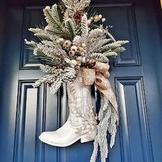 a boot decorated with pine cones and evergreens hangs on the front door's blue door