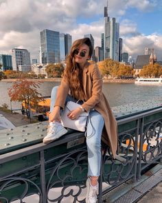 a woman sitting on top of a bridge next to the water