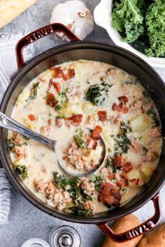 a pot filled with meat and cheese soup on top of a table next to a bowl of broccoli